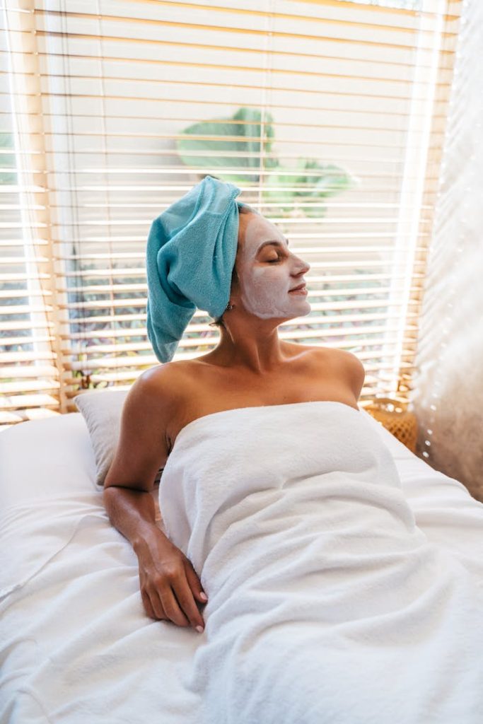 pexels-photo-6560345 A woman enjoys a relaxing spa day with a facial mask and towel wrap in a serene indoor setting.